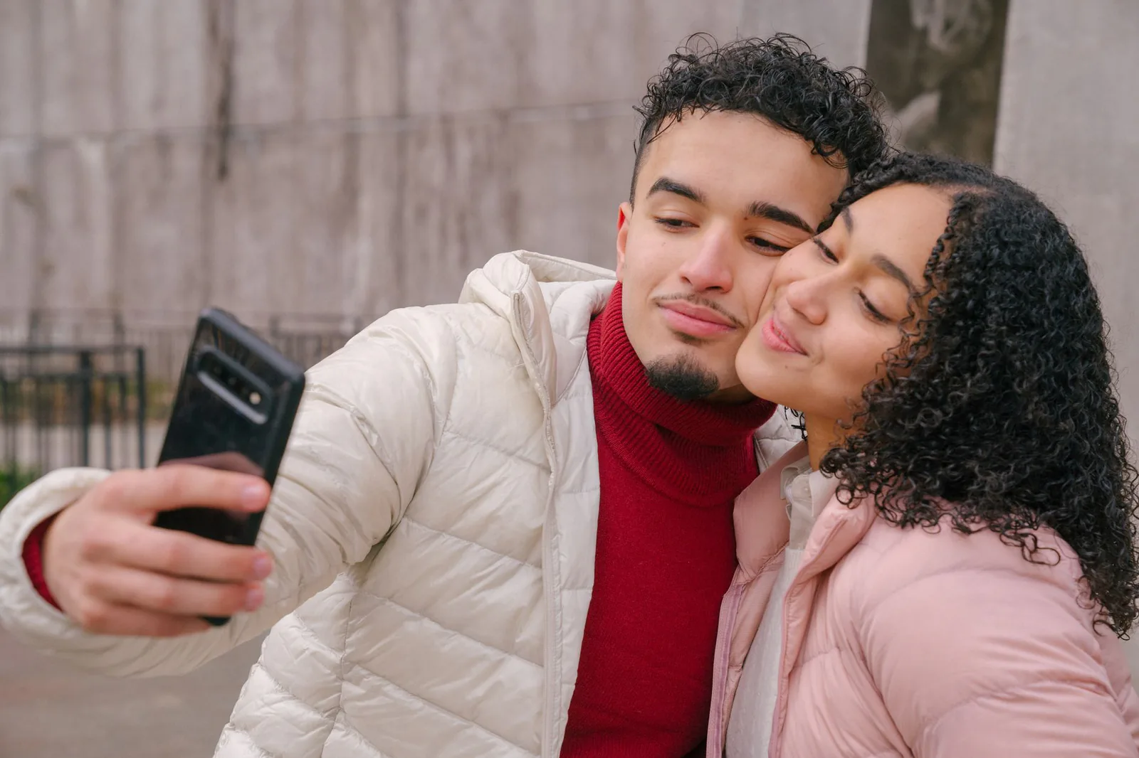 A smiling young couple taking a selfie together on the street