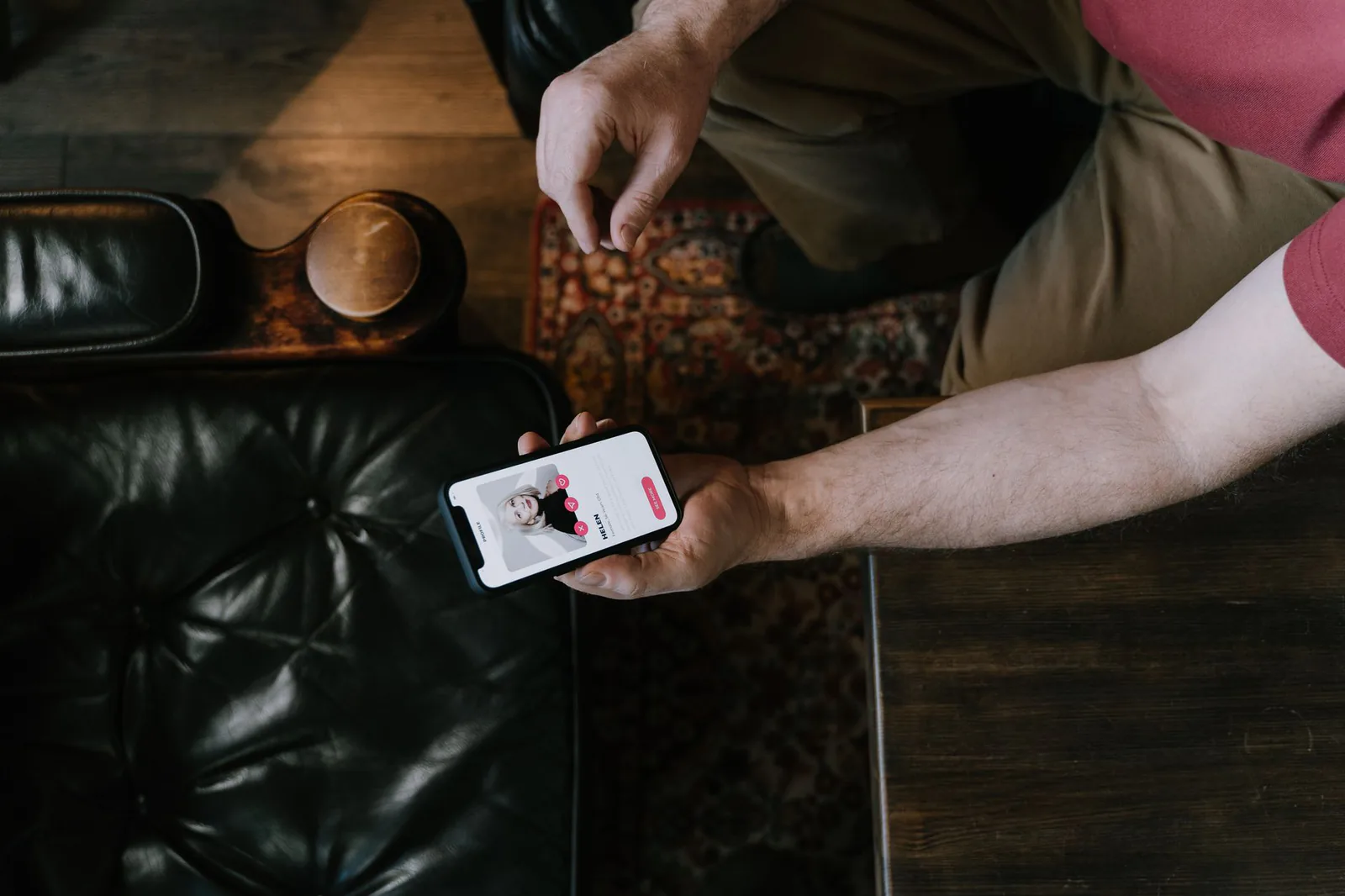 A person sitting in a chair holding a smartphone with a dating app open